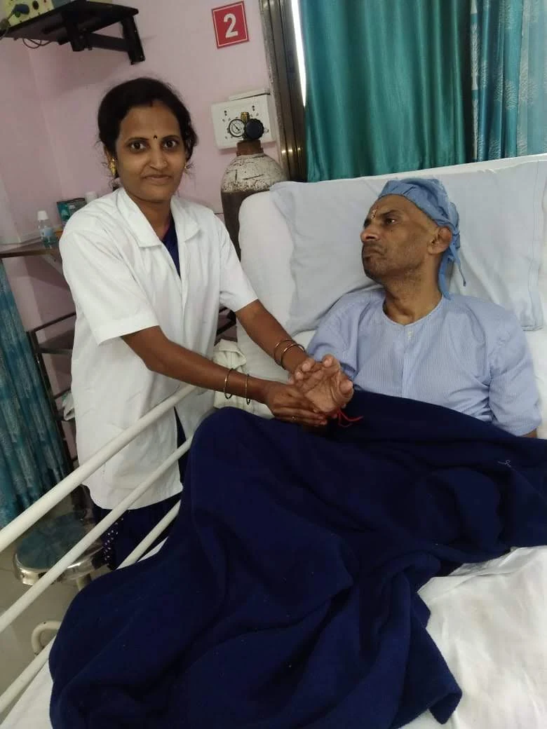 A care worker holding the hand of a patient at Jeevan Jyoti