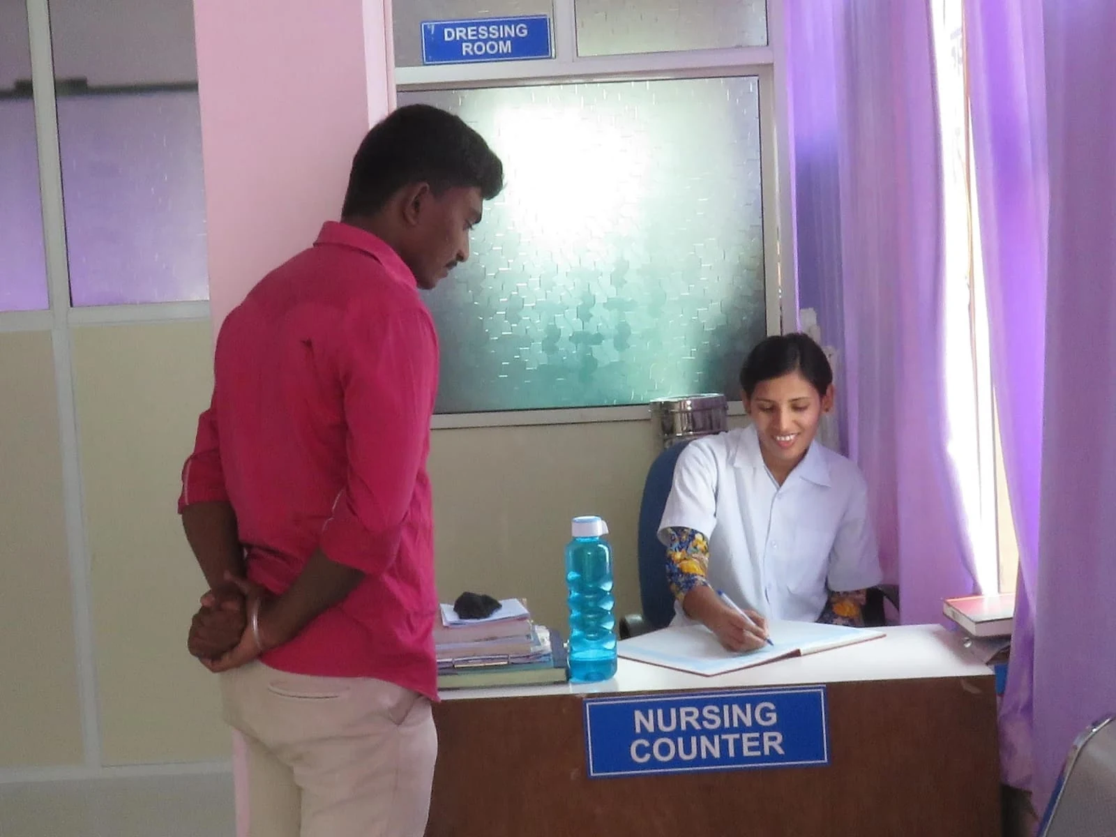 A staff member speaking with a visitor at the nursing counter