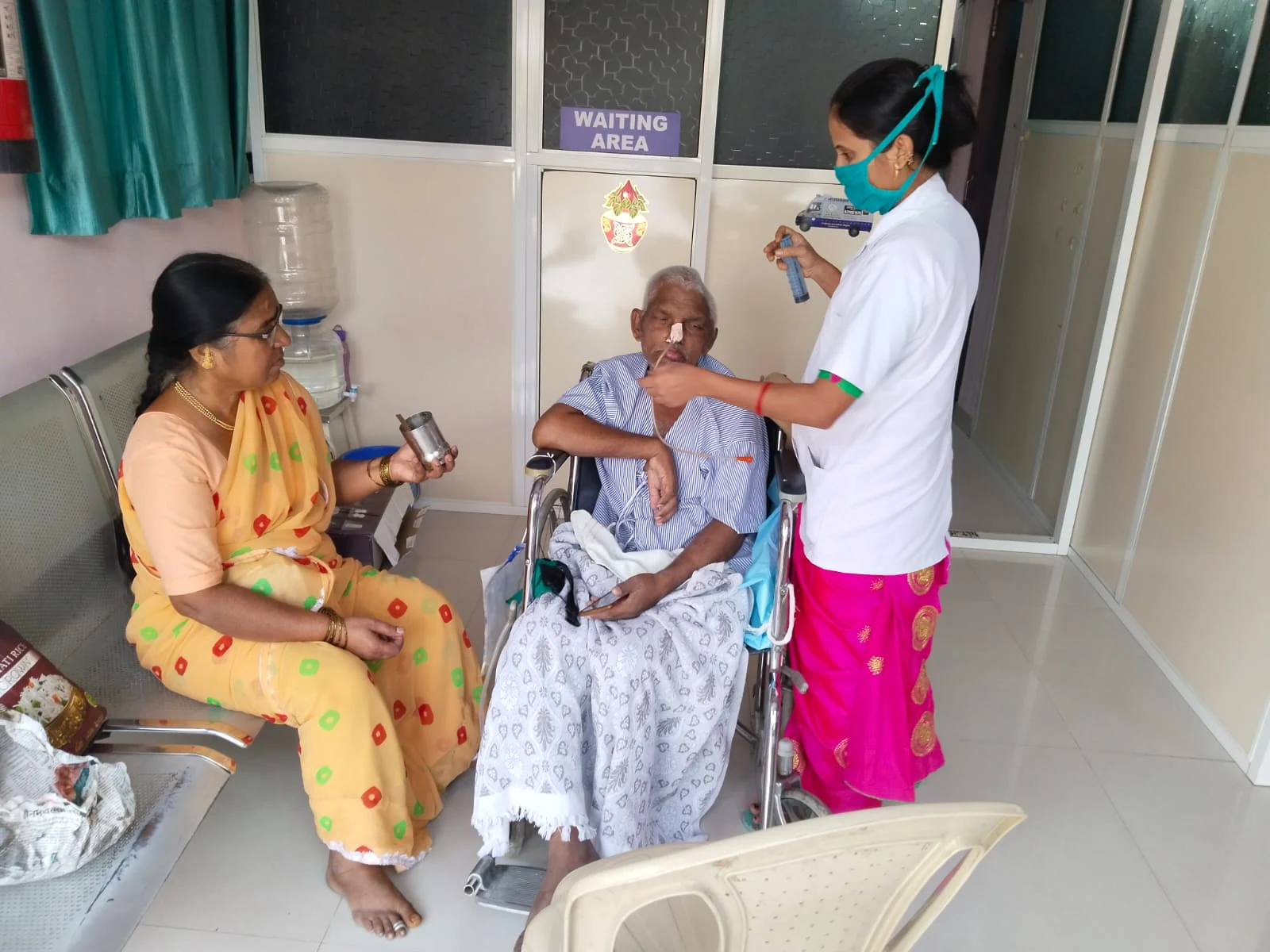 A care worker assisting an older man with another person nearby at Jeevan Jyoti