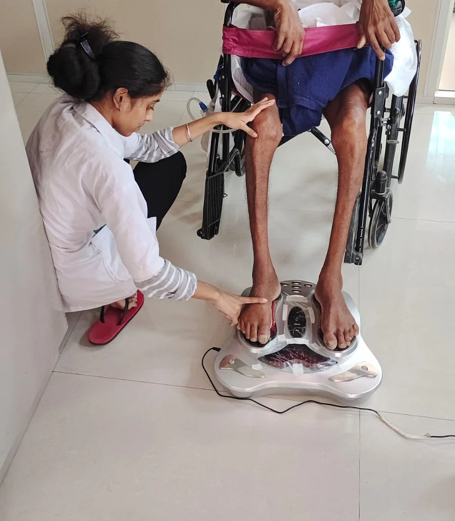 A therapist guiding a patient's leg movement at Jeevan Jyoti