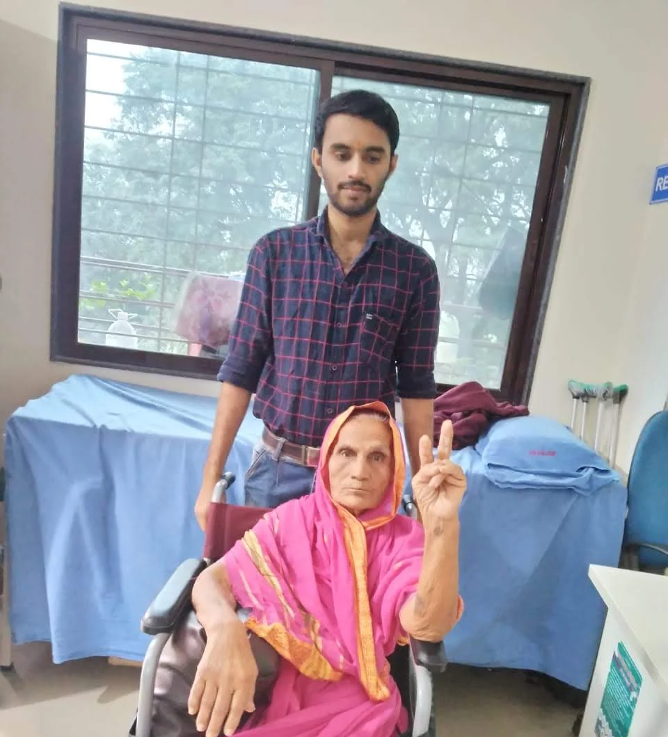 An older woman in a wheelchair with another person nearby at Jeevan Jyoti